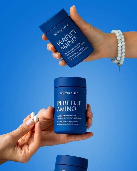 A high-contrast, clean 4:5 creative displaying supplement jars held in hands against a vibrant blue studio background.